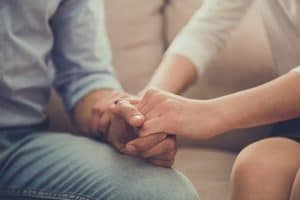 people hold hands on a couch as they learn about depression treatment program